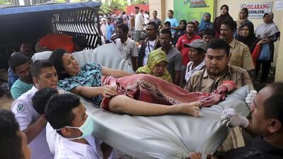 Hospital workers and family members carry a woman injured in the earthquake. Heri Juanda / AP Photo