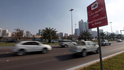 Motorist drive along the Corniche past a sign postings warning of speed enforcement by radar. Sammy Dallal / The National