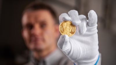 Designer and engraver Thomas Docherty with the UK £5 gold coin unveiled before Prince William's 40th birthday. Royal Mint / PA