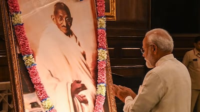 India's Prime Minister Narendra Modi gestures beside a portrait of Indian independence icon Mahatma Gandhi at Parliament House in New Delhi on October 2, 2019 to mark Gandhi's 150th birth anniversary. AFP