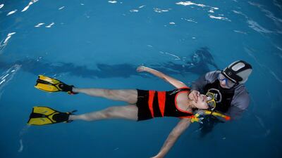 A young swimmer is taught to float in the water by Basra swimming coach Elaf. Reuters
