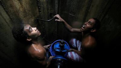 Locals collect water from an underground water main pipeline in Caracas, Venezuela. Reuters