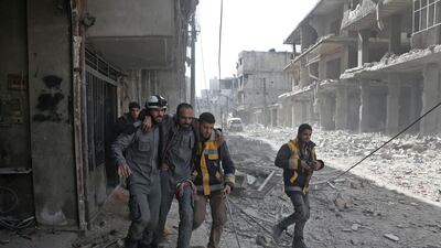 Volunteers from the Syrian civil defence help a man in Hamouria during Syrian government shelling on rebel-held areas in the Eastern Ghouta region on the outskirts of the capital Damascus on March 6, 2018. Abdulmonam Eassa / AFP