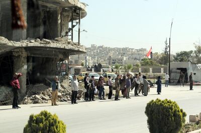 People standing in front of a building destroyed in the Syrian conflict. Youssef Badawi / EPA