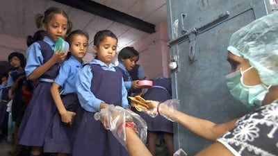 Schoolgirls collect free midday meals at government-run primary school in New Delhi. India may soon pass a new law to give millions more people cheap food. Mansi Thapliyal / Reuters