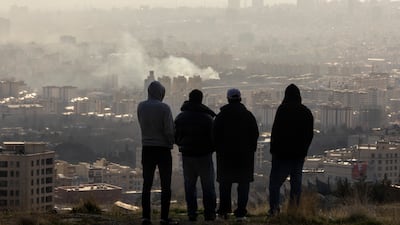 Men watch from a hillside as a plume of smoke rises after an explosion in Tehran, Iran, in March. Getty Images