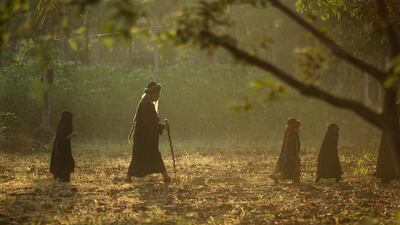 A man with his grandchildren from the Islamic commune An Nadzir walk through oil palm plantation to attend Eid Al Adha prayers at Mawang Lake, Gowa Regency Makassar, Indonesia. Agung Parameswara / Getty Images