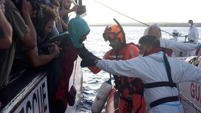 Migrants are evacuated by Italian Coast guard personnel from the Open Arms Spanish humanitarian boat off the coast of Lampedusa, southern Italy, on Thursday. AP