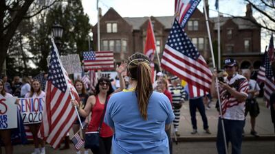 A woman who identified herself as a registered nurse in a local emergency room counterprotests in front of a demonstration to open up the state from the restrictions in place due to the new coronavirus, organized by the 3% United Patriots group, outside the Governor's Mansion in St. Paul, Minn. AP
