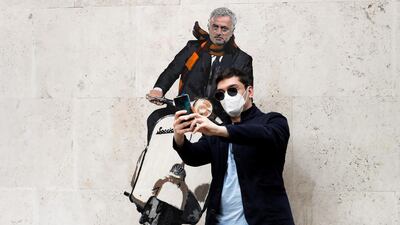 A man takes a selfie with a mural depicting new AS Roma coach Jose Mourinho riding a Vespa on a wall in Rome. Reuters