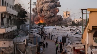 Palestinians run for cover as smoke and fire rise during an Israeli strike on the the Al-Muttaqin Mosque in Gaza City. AFP