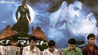Pedestrians sit in front of a poster for 'Krrish'.