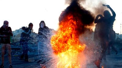 A Palestinian demonstrator kicks a burning tire during clashes with Israeli forces near a checkpoint in the West Bank city of Ramallah. Abbas Momani / AFP Photo