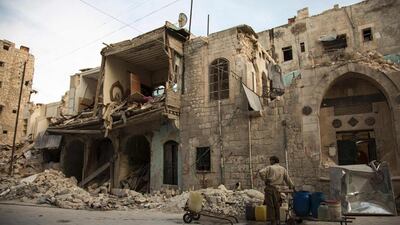 A Syrian man waits to fill jerricans with water in front of destroyed buildings in Aleppo's Bab al-Hadid neighbourhood, Syria. Karam Al Masri / AFP