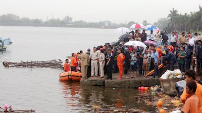 People stand on the shore of a lake as members of India's National Disaster Response Force conduct a rescue operation at Khatlapura Ghat in Bhopal, India 13 September 2019. According to media reports, at least 11 people drowned after an overloaded boat capsized during the Ganesh Chaturthi festival. EPA