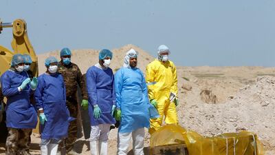 Iraqi Shiite volunteers from Hashid Shaabi (Popular Mobilization Forces) and members of a medical team wearing protective suits, pray near the coffin of a man who passed away due to coronavirus on the outskirt of Najaf, Iraq. Reuters