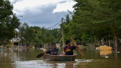 Residents ride a boat through floodwaters in Mentakab in Malaysia's Pahang state following heavy rains. AFP