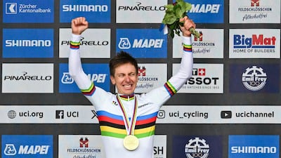 Tadej Pogacar celebrates on the podium in the world champion's rainbow jersey after his victory. AFP
