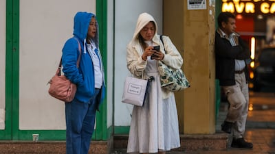 People wrap up after rain falls in Abu Dhabi. The UAE is experiencing a cold snap, with temperatures dropping to 2ºC in Ras Al Khaimah's mountains. Victor Besa / The National