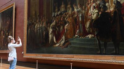 A visitor takes a photo of an artwork at Louvre as it reopens its doors. Getty Images