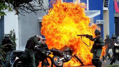 Riot security forces clash with demonstrators as a motorcycle is set on fire during a prostest in Venezuela. Carlos Eduardo Ramirez / Reuters