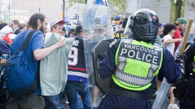 Police stand in front of people on the street following Game 7 of the Stanley Cup finals.