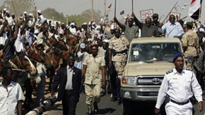 Sudanese president Omar al Bashir, top second right, waves his cane in the air as supporters greet him in the North Darfur state capital of el-Fasher.