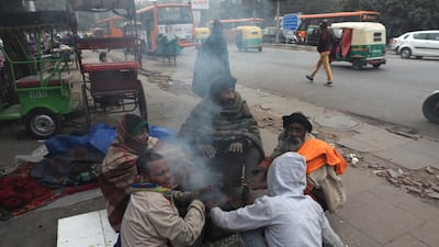 epa08095601 People sit next to a fire on a cold morning in New Delhi, India, 31 December 2019. Northern India remains in the grip of cold as minimum temperature in the national capital New Delhi dropped below the three degrees Celsius mark. EPA/RAJAT GUPTA