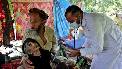 A doctor tends to an injured Afghan woman outside her damaged house in Kunar province. Reuters