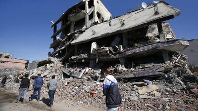 People walk past ruined buildings in Cizre, Turkey. Emrah Gurel / AP Photo