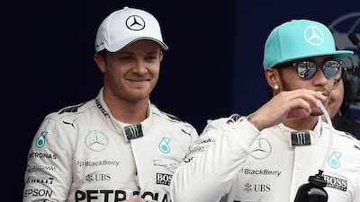 Mercedes driver Lewis Hamilton, right, takes a drink after taking pole position while teammate Mercedes driver Nico Rosberg looks on following the qualifying race at the Formula One Malaysian Grand Prix in Sepang on March 28, 2015. AFP PHOTO / MANAN VATSYAYANA