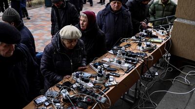 People charge their mobile phones in a public building in Bucha. AFP