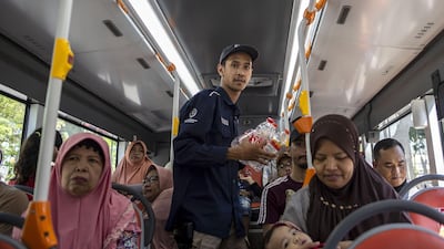 A bus conductor collects used plastic bottles as fare payment.