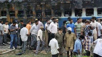 Railway workers and officials inspect the burnt coach of a passenger train at Nellor.