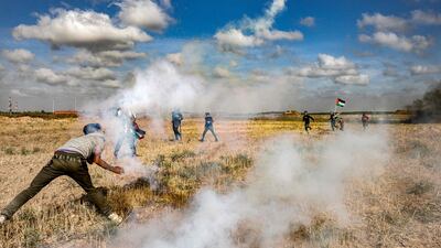 Protesters throw back tear gas grenades fired by Israel during a demonstration at the Gaza border. AFP