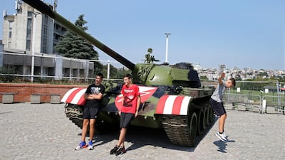 People pose for a photograph in front of a former Yugoslav army T-55 battle tank in front of the northern stand of the Rajko Mitic stadium in Belgrade. EPA