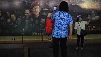 Visitors taking photos in front of a mural, illustrating the rescue of the 12 boys and their coach. AFP