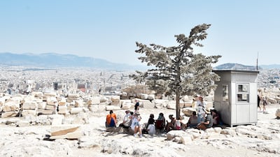 Tourists shelter from the sun atop the Acropolis in Athens. Getty Images