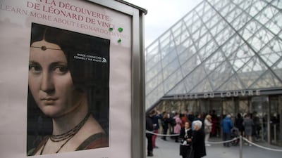 A poster for the exhibition 'Leonardo da Vinci' is seen in front of The Louvre Museum in Paris as visitors queue on the day of the exhibition's opening. AFP