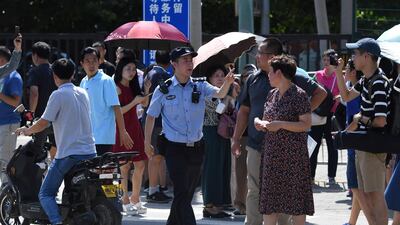 A Chinese police officer gestures among a crowd of bystanders gathered outside the US embassy in Beijing. AFP