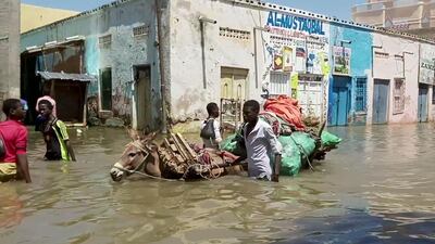 In this image made from video taken Sunday, May 17, 2020, people wade through a flooded street in Beledweyne, central Somalia. Flooding in central Somalia has affected nearly 1 million people, displacing about 400,000, the United Nations said Monday, May 18, 2020 warning of possible disease outbreaks because of crowding where the displaced are seeking temporary shelter. (AP Photo)