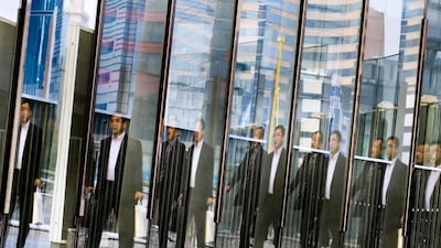 Men are reflected in a glass railing as they walk at the Shiodome business district in Tokyo on November 12, 2014. Japanese companies overwhelmingly want prime minister Shinzo Abe to delay or scrap a planned tax increase, a Reuters poll shows, highlighting concerns that it could derail a fragile economic recovery. Thomas Peter / Reuters