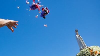 A pilgrim throws flowers at the statue of Our Lady of Fatima during a procession on the second day of the annual international pilgrimage to the Shrine of Fatima in Portugal. EPA