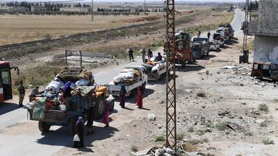 Syrian soldiers stand guard by a convoy returning displaced people home into government-controlled territory at Abu al-Zuhur checkpoint in the western countryside of Idlib province. George Ourfalian / AFP