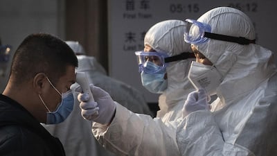 A Chinese health worker checks the temperature of a person entering a subway station in Beijing, China. Getty Images