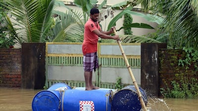 An Indian man paddles down a street on a makeshift raft. EPA