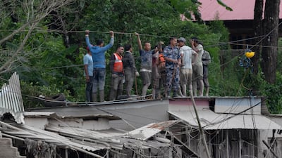 Rescuers gather on a rooftop as floodwater gushes through Trishuli Bazar. EPA