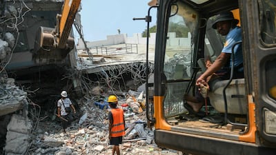 Heavy construction equipment is used to dig through the rubble as people look for survivors in a destroyed building in Mandalay, Myanmar. AFP