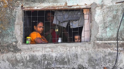 Members of a family look out of a window of their home at the Dharavi slum. AFP