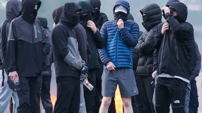 Masked youths block a road with burning debris. AFP